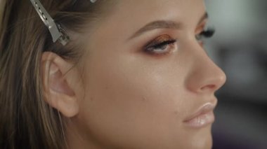 Genç profesyonel kadın photomodel çehresini Güzellik Salonu Makyaj süreci sırasında kapatın. Genç visagiste özel fırça kullanarak göz kapağı üzerinde göz farı uyguluyor.
