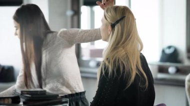 Güzellik Salonu. Bir makyaj master model göstermek için hazırlar. Kız bir üst göz kapağı istemci üzerinde bir gölge fırça ile uygulanır. Makyaj sanatçısı, profesyonel bir makyaj yapar.