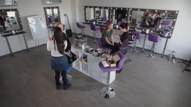 Blogger de belleza en el maquillador. Dos novias en el salón de belleza. Artistas de maquillaje entrenan a dos chicas para la filmación de video. El estudio es muy acogedor . — Vídeo de stock