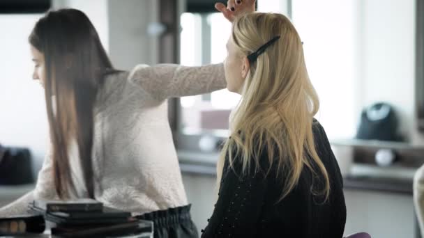 Beauty shop. The master in a make-up prepares model for display. The girl applies with a shadow brush on an upper eyelid of the client. The makeup artist professionally does a make-up. — Stock Video