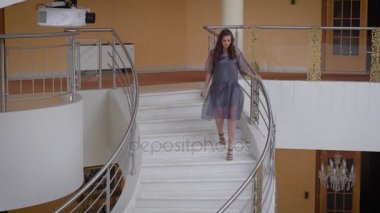 Photomodel beyaz sırasında kuliste profesyonel fotoğrafçılığın basamaklardan iniyor. Kameraya bakarak ve resim için poz zengin salonu aşağı gidiş mavi elbiseli uzun saçlı kız.