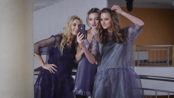 Drie vriendinnen na een succesvolle campagne in de trendy schoonheidssalon verlichten zichzelf op de front camera van de smartphone en vervolgens foto's uploaden naar een sociaal netwerk. Dwaze jonge meisjes. — Stockvideo