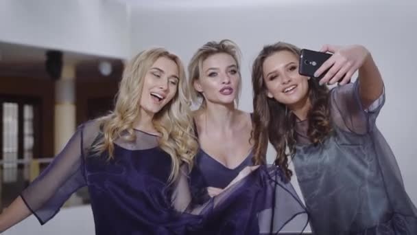 Tre glada väninnor gör roliga selfie ler lyckligt. Sexig chic flickor firar jubileum och deltar i födelsedagsfest. Damer är avkopplande och njuta av tiden tillsammans. — Stockvideo