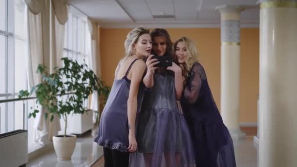 Modelos elegantemente vestidos fizeram selfie no smartphone quando um deles lembra que precisam se apressar para o desfile de moda. Garotas engraçadas tolas fugindo na direção da porta . — Vídeo de Stock