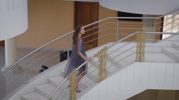 Spruced dziewczyna z żelaza włosów na likwidacji marmurowe schody. Piękno sobie Projektant sukienka wykonana z tkaniny syntetycznej, wygląda jak świadka ślubu lub urodzin dziewczyny — Wideo stockowe