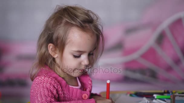 Hermosa niña en cárdigan rosa dibujando la ilustración con lápices en el jardín de infantes. El niño pequeño está pintando la imagen del cumplido para la madre con bolígrafos de punta suave que eligen diferentes colores . — Vídeos de Stock