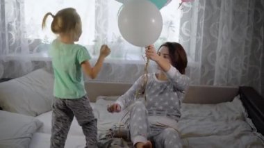 Anne ile kızı odaya oynanır. Kız bir yatakta bir pijama atlar. Kızın ellerinde çok renkli balonlar var. Bebeğin balonları yener ve kadın topları arka arkasında gizler.