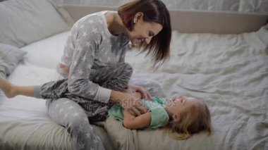 Oynama ve evde yatakta sarılma mutlu bir aile. Ablası şaka yollu gidiyor ona küçük bir tane ve onlar her iki gülüyor.