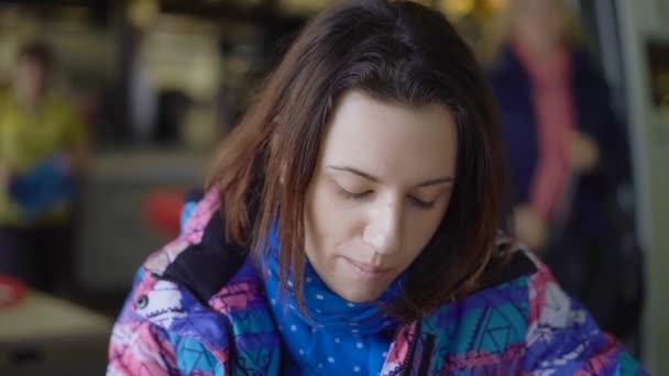 La chica corrió a la cafetería de la calle, que rápidamente comer. La morena se sienta en una chaqueta deportiva y come papas fritas en un restaurante de comida rápida . — Vídeos de Stock