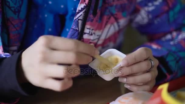 La ragazza corse nel caffè dalla strada, che avrebbe rapidamente mangiare. La bruna si siede in una giacca sportiva e mangia patatine fritte in un ristorante fast food . — Video Stock