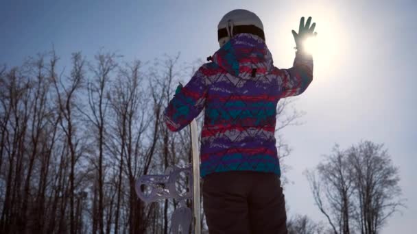 Atmospheric frame, the concept of dreams and joy of the day. A snowboarder girl catches a bright sun with her hand. A clear winter day in the mountains — Stock Video