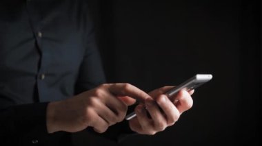 Kavramı, dijital online yaşam ve sosyal ağlar. Bir işadamı bir gömlek onun smartphone onun hesapları görüntülemek için kullanır. Etkileyici atış, karanlık bir odada bir adam şık bir telefon tutarak