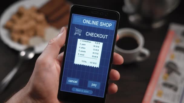 Πληρώνοντας ένα κατάστημα receipe με μια εφαρμογή για smartphone. Στο πλαίσιο της επανδρώνει τα χέρια, πρόσωπο πληρώνει για τις αγορές σε ένα online κατάστημα μέσω Internet και του smartphone. Έλεγχος για οικοδομικά υλικά και εργαλεία — Αρχείο Βίντεο