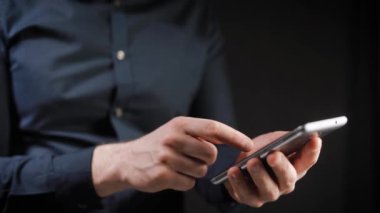 Kavramı, dijital online yaşam ve sosyal ağlar. Bir işadamı bir gömlek onun smartphone onun hesapları görüntülemek için kullanır. Etkileyici atış, karanlık bir odada bir adam şık bir telefon tutarak