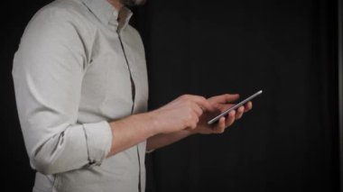 Kavramı, dijital online yaşam ve sosyal ağlar. Bir işadamı bir gömlek onun smartphone onun hesapları görüntülemek için kullanır. Etkileyici atış, karanlık bir odada bir adam şık bir telefon tutarak