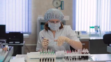 Kan testi analiz ve laboratuar alt tarafından deyimleri tüpleri. Hastanede tıbbi laboratuvar çalışmalarında. Koruyucu maske ve gözlük bir kadın hastaların kan örneği sıralar.