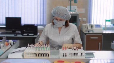 Kan testi analiz ve laboratuar alt tarafından deyimleri tüpleri. Hastanede tıbbi laboratuvar çalışmalarında. Koruyucu maske ve gözlük bir kadın hastaların kan örneği sıralar.