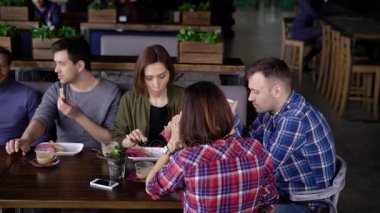 Mola sırasında öğle yemeği zaman yaratıcı modern giyimli arkadaşlar bir araya geldi. Kızlar ve erkekler için bir sandviç ve içecek kahve yemek için office için yorum yaptı. Arkadaşlar sizin en sevdiğiniz kafede çeşitli konularda iletişim kurmak.