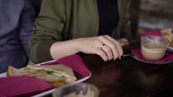 Amigos vestidos modernos creativos se reunieron a la hora del almuerzo durante el descanso. Niñas y niños salieron de la oficina para comer un sándwich y tomar café. Los amigos se comunican sobre varios temas en su cafetería favorita . — Vídeos de Stock