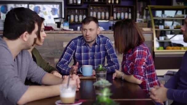 Los amigos están sentados en un café y tomando café y té. Amigos de los estudiantes no se han visto desde hace mucho tiempo y decidieron reunirse en su restaurante favorito . — Vídeos de Stock