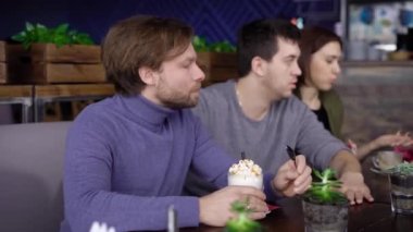 Sarı saçları ve sakalı bir mor Kazak giymiş, bir yetişkin orta yaşlı adamla zevk frappuchino kahve ile krem şanti ile içecekler