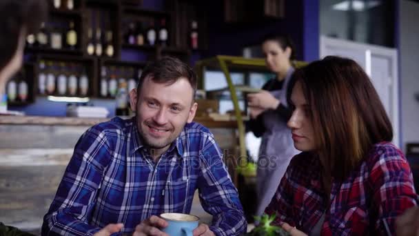 Vários amigos adultos conversam no restaurante, bebendo café americano, cappuccino e latte, que ficam em cima da mesa. Empresa feliz agradável conversando uns com os outros — Vídeo de Stock