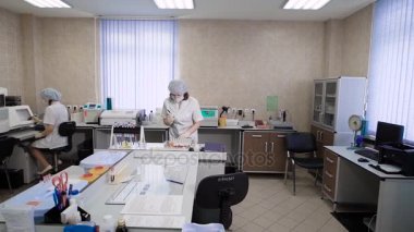 Laboratuvarda çalışan diğer uzmanlar. Kadın klinik laboratuvar analizleri ile çalışan beyaz üniformalı.