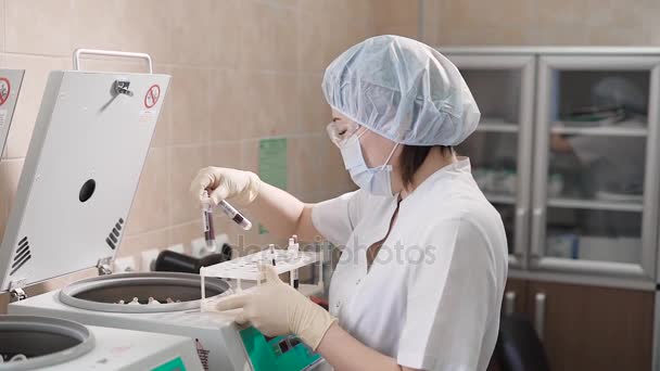 Especialista feminina colocando espécime em centrifugadora. Jovem especialista em uniforme colocando espécime com sangue em centrífuga . — Vídeo de Stock