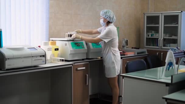Especialista en centrifugadoras. Especialista femenina en uniforme blanco encendiendo centrifugadora con muestra de sangre . — Vídeos de Stock