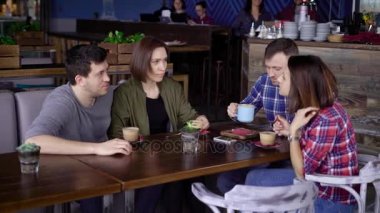 Onların yemek keyfi ve Birbirinizle konuşmak kafede masada oturan dört arkadaş. İki çiftler restoranda yemek yerken sohbet. İçme ve birlikte yemek kadın ve erkek.