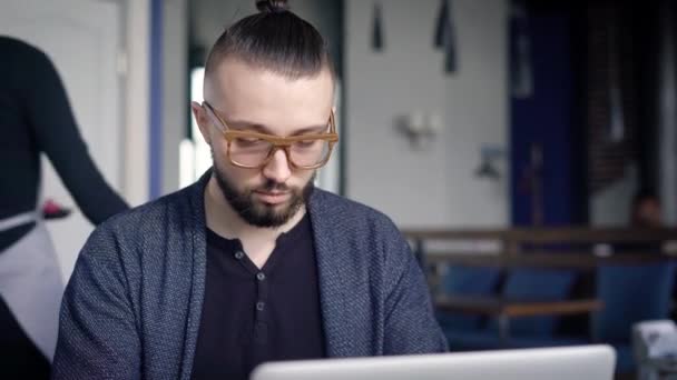 Podnikatel, pracují na přenosném počítači v tabulce. Mladý muž s brýlemi vypadá bokovky. Ležérní vzhled