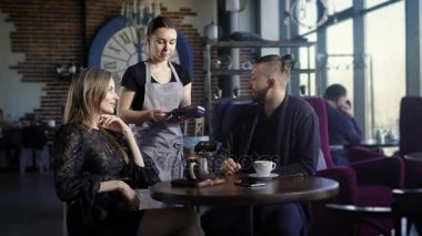 Şık bir kafede yemeğin sonuna. Adam ve kız ödemeye hazırız, adam kredi kartını kullanır, PIN girmek garsona sorar. Modern kablosuz bankacılık
