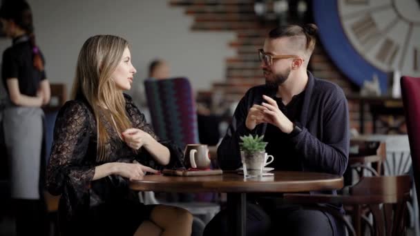 Mensen uit het bedrijfsleven tijdens de lunch break in een café. Twee mannen en een vrouw praten over werk tijdens de lunch. Mooie jonge mensen, ontwerpers of managers communiceren over onderwerpen van de werken. — Stockvideo