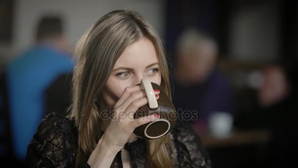 Portret pięknej młodej kobiety w kawiarni. Ona pije kawę i słucha rozmówcy, a następnie odpowiada na to. Kobieta biznesu w przerwie obiadowej — Wideo stockowe