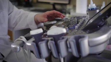 Denetim Kurulu aygıt için ultrason hastanede tanı ve tıbbi cihazlar kullanılıyor ve diffent düğmeleri koyarak beyaz paltolu bir doktor erkek el yakın çekim.