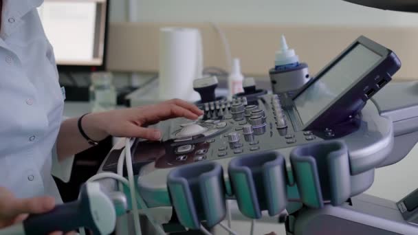 Detailní záběr z ovládacího pultu tohoto zařízení pro ultrazvukové diagnostiky. Doktor v bílém úboru snímače drží v ruce a používání lékařského vybavení pro sonografii a skenování viscerálních orgánů pacienta. — Stock video