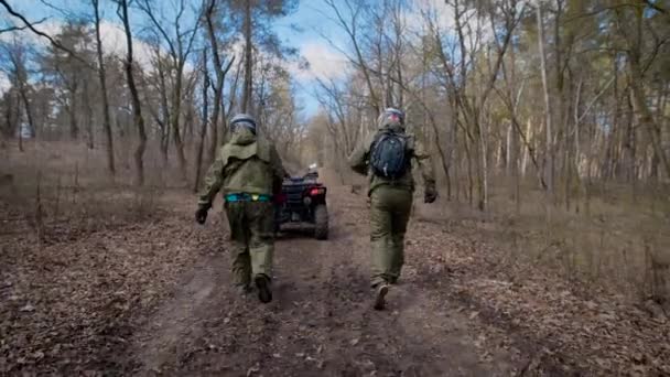 Два спортсмена, которые носят защитные шлемы и одежду, прыгают на квадроциклах и быстро ездят по осеннему лесу — стоковое видео