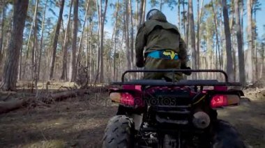 Extreme sürüş seven genç bir adam yolda küçük engellerin üstesinden sonbahar ormana quad bisiklet sürmek