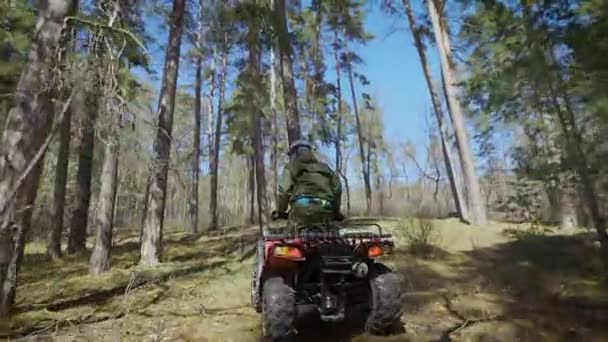 Um homem adulto, sobe um veículo todo-o-terreno para cima em uma estrada áspera, uma pessoa monta uma moto quad e dirige o veículo com um leme — Vídeo de Stock