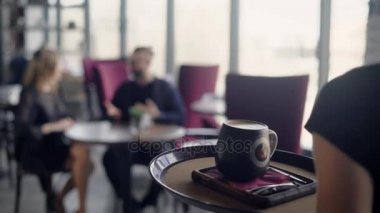 Garson genç çiftin bir restoranda bir aperatif gerçekleştiren tepsisindeki büyük cappuccino Kupası giyer, bir erkek ve bir kadın geçtiğimiz hafta sonu hakkında konuşmak