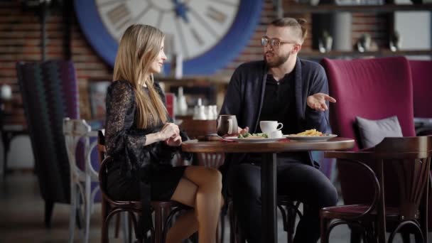 Restoranda öğle vakti, bir adam ve güzel bir kadın uzun sarı saçlı son çalışma günü hakkında konuşurken komik anlar gülüyor çalışma arkadaşları — Stok video