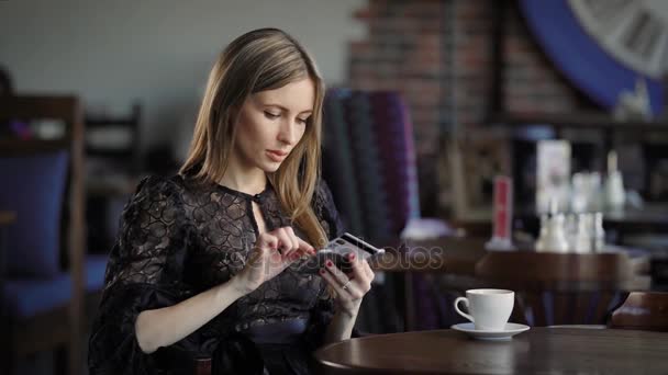 En ung kvinna som gick in i en restaurang för att dricka kaffe och äta träder detaljerna i sitt bankkort i mobilt Internet betala för parkering sin bil — Stockvideo