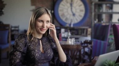 Cep telefonu eşine konuşmak güzel bir iş kadını genç bir kadın o şimdi hangi ayakları üzerinde ahşap bir masa üzerinde çalışmak için bir dizüstü oturur rahat bir kafede bir toplantı düzenler.