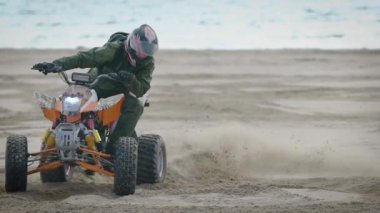 Nehir banka. Yarışçı hareketleri quad bisiklet üzerinde çalışıyor. Adam kum sürüş Atv çalışmalar hakkında.