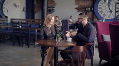 Misafirperver genç garson kadın için tabloya kahverengi seramik kupa içecek getiriyor. Oturma bir araya gelip konuşan restoranda kaç. Kafeteryada kahve molası arkadaşları.