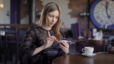 Bayan smartphone içinde belgili tanımlık geçmiş insanlarla restoranda oturan bir kredi kartı ile online satın alma. Nakitsiz ödeme için istimal modern telefon ve Internet üzerinden alışveriş yapma siyah elbiseli kadın.