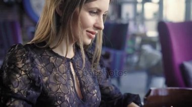 Kafede oturan ve modern dizüstü kullanarak siyah seksi decolette içinde güzel kadın kapatın. Dijital aygıt üzerinde metin yazarak tablo mobil ofis içinde bir freelance çalışan iş kadını.