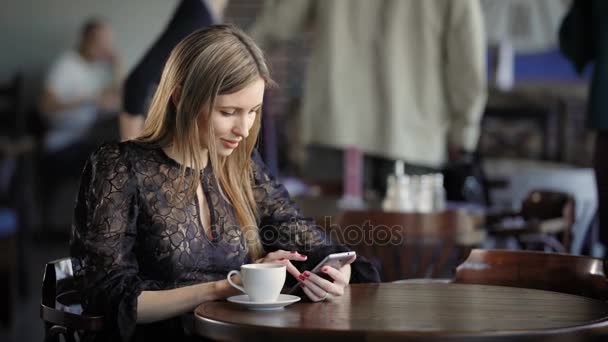 Крупним планом красива жінка, проводити вільний час за допомогою сучасного смартфону та перегляду сторінок Інтернету. Чарівні леді відпочити в кафе під час обіду з чашкою напоїв і цифрового пристрою. — стокове відео