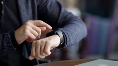 Kırpma görüntüsünü zaman kontrol adam. Erkek kafede otururken smartwatch kullanarak kırpma vurdu.