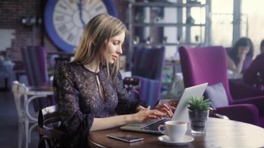 Kafede dizüstü güzel kadın var. Kafede oturan ve dizüstü bilgisayar kullanarak kahve Kupası ile güzel kadın.